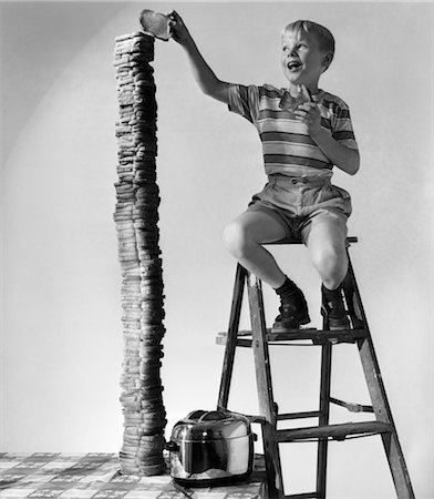 sprecare - 1950s SMILING BOY ON LADDER STACKING UP LARGE TOWERING PILE OF TOASTED BREAD Fotografie stock - Rights-Managed, Codice: 846-02793734