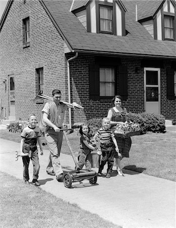 ANNÉES 1950 FAMILLE DE CINQ PERSONNES SUR TROTTOIR SUBURBAN MARCHANT AU JARDINAGE OUTILS TONDEUSE & FLEURS Photographie de stock - Rights-Managed, Code: 846-02793756