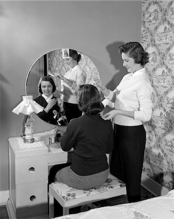 1950s TEEN GIRL SITTING AT VANITY ROUND MIRROR AS ANOTHER DOES STYLES HER HAIR Stock Photo - Rights-Managed, Code: 846-02793760