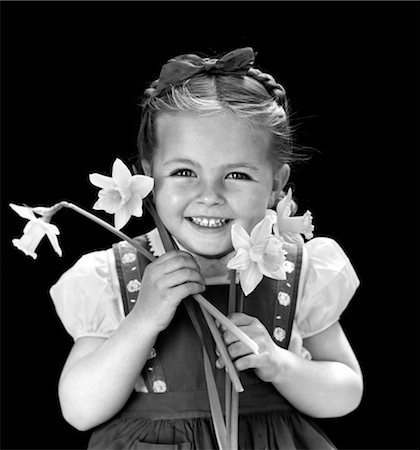 1940s SMILING GIRL HOLDING SPRING DAFFODILS WEARING JUMPER WITH HAIR BRAID HELD ON TOP OF HEAD WITH BOW Stock Photo - Rights-Managed, Code: 846-02793807