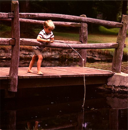 1960s BAREFOOT BLOND BOY WOODEN BRIDGE FISHING POLE POND STREAM Stock Photo - Rights-Managed, Code: 846-02793876