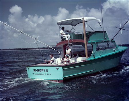 popa - 1950s MAN WOMAN FISHING OFF BACK STERN TURQUOISE CHARTER BOAT TWO MAN CREW WHITE BIMINI HI HOPES FT LAUDERDALE FL Foto de stock - Con derechos protegidos, Código: 846-02793885