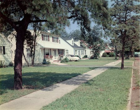 simsearch:846-02797677,k - 1950s SUBURBAN STREET WHITE HOUSES WITH SIDEWALK RUNNING DOWN MIDDLE OF IMAGE YARD GREEN GRASS SPRING LAKE NJ Stock Photo - Rights-Managed, Code: 846-02793935