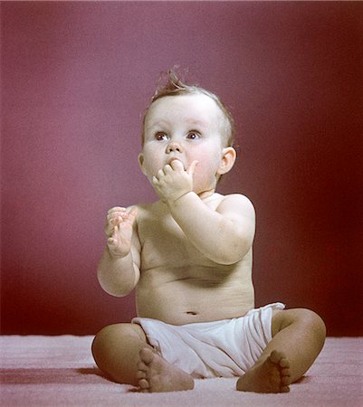 1940s 1950s BABY DIAPER SITTING LOOKING UP FINGERS IN MOUTH Stock Photo - Rights-Managed, Code: 846-02793971