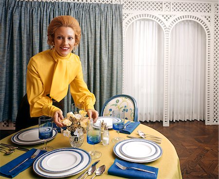 1970s WOMAN HOSTESS YELLOW TIE BLOUSE FLOWERS ON DINING TABLE BLUE WHITE CHINA DISHES HOUSEHOLD HOME ENTERTAINING Foto de stock - Con derechos protegidos, Código: 846-03164218