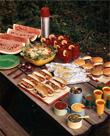 50ER JAHRE-PICKNICK-TISCH OBEN VOLLER ESSEN HOTDOGS HAMBURGER WATERMELON SALAD THERMOS GEWÜRZE HINTERHOF SOMMER MAISMEHL Stockbilder - Lizenzpflichtiges, Bildnummer: 846-03164282