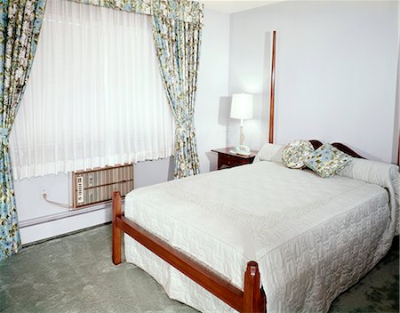 1960s BEDROOM WITH FULL SIZE BED WINDOW WITH FLORAL PRINT DRAPES SHEERS AND AIR CONDITIONER Stock Photo - Rights-Managed, Code: 846-03164667