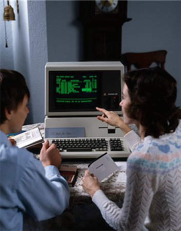 década de 1980 - 1980s COUPLE WORKING AT APPLE III 3 HOME COMPUTER PAYING BILLS Foto de stock - Direito Controlado, Número: 846-03164662