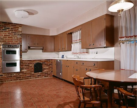 1970s KITCHEN WITH DARK WOODEN CABINETS BRICK WALL AND DOUBLE OVEN Stock Photo - Rights-Managed, Code: 846-03164686