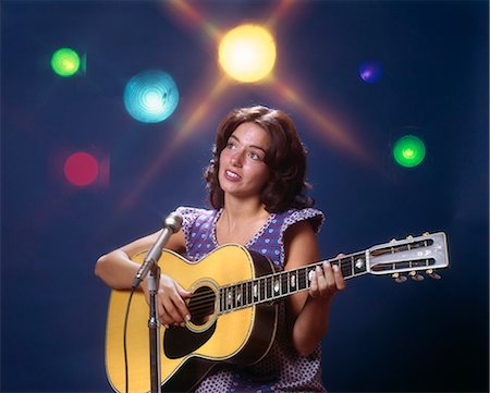 simsearch:846-03165060,k - 1970s WOMAN GIRL PERFORMER PLAYING GUITAR SINGING MICROPHONE STAGE LIGHTS FOLK SINGER Stock Photo - Rights-Managed, Code: 846-03165008