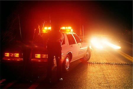 POLICE ROAD BLOCK, TWO POLICE OFFICERS BEHIND PATROL CAR AND MALE IN ONCOMING CAR Stock Photo - Rights-Managed, Code: 846-03165211