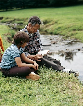 1970s MAN AND BOY FATHER SON OUTDOOR BY STREAM READING BIBLE Foto de stock - Con derechos protegidos, Código: 846-03165580