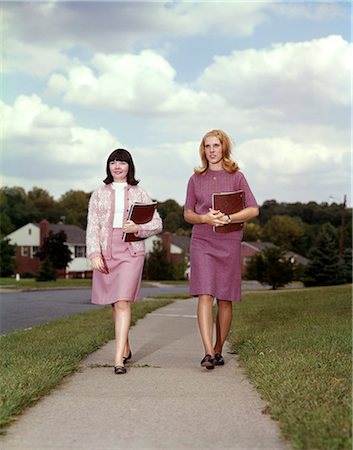 1960s TWO TEEN GIRLS CARRYING BOOKS WALKING DOWN SIDEWALK Stock Photo - Rights-Managed, Code: 846-03166001