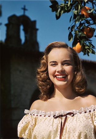 1940s 1950s PORTRAIT SMILING TEEN GIRL WEARING OFF THE SHOULDER LACE BLOUSE POSING BY ORANGE TREE CHURCH CROSS STEEPLE IN BACKGROUND Stock Photo - Rights-Managed, Code: 846-03166354