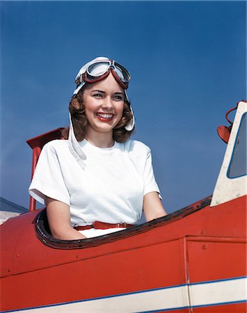 1930s 1940s 1950s SMILING WOMAN WEARING PILOTS HELMET GOGGLES SITTING IN AIRPLANE COCKPIT Fotografie stock - Rights-Managed, Codice: 846-03166365