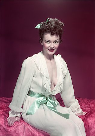 1940s 1950s SMILING WOMAN WEARING WHITE NEGLIGEE SLIP ROBE POSING SITTING ON EDGE OF BED Foto de stock - Con derechos protegidos, Código: 846-03166378