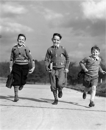 simsearch:846-02797866,k - 1930s THREE BOYS RUNNING CARRYING SCHOOL BOOKS Stock Photo - Rights-Managed, Code: 846-03163194
