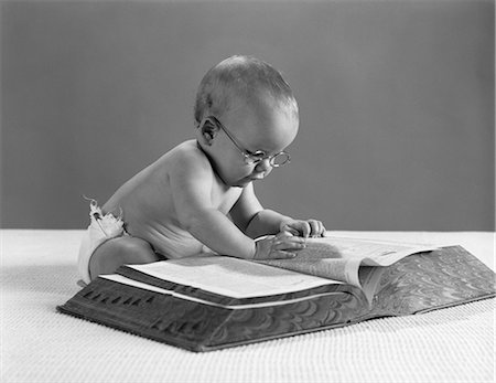 1960s BABY WEARING GLASSES LOOKING FOR A WORD IN BIG DICTIONARY Foto de stock - Con derechos protegidos, Código: 846-03163223