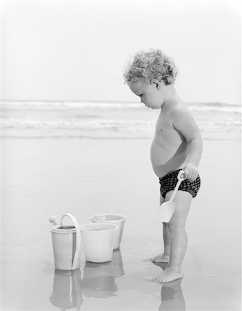 1970s CHILD TODDLER STANDING IN SAND WATER BUCKET SHOVEL Stock Photo - Rights-Managed, Code: 846-03163417