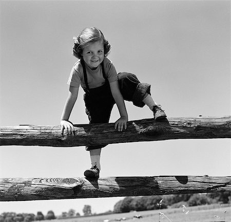 1940s 1950s SMILING GIRL CLIMBING OVER WOODEN FENCE Stock Photo - Rights-Managed, Code: 846-03163439