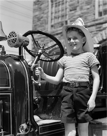 1940s CHILD STANDING NEXT TO FIRE ENGINE HAT SMILING Stock Photo - Rights-Managed, Code: 846-03163592