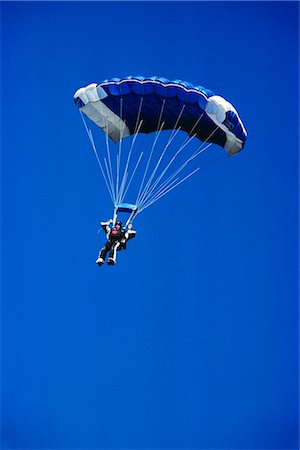 sky diver - SKYDIVER WITH OPEN BLUE AND WHITE PARACHUTE IN BLUE CLOUDLESS SKY Foto de stock - Con derechos protegidos, Código: 846-03163640