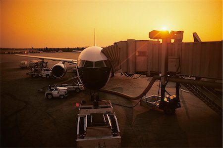 1980s FRONT VIEW OF AIRPLANE BOARDING TUNNEL ATTACHED SUN IN BACKGROUND Stock Photo - Rights-Managed, Code: 846-03163657