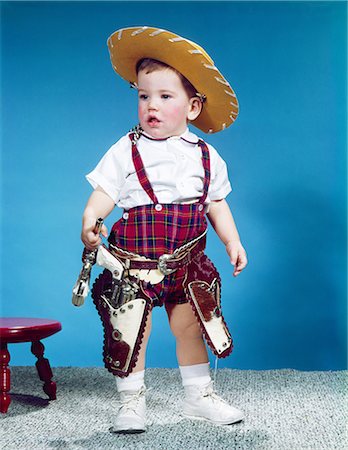simsearch:846-02794068,k - 1960s BABY BOY TODDLER STANDING WEARING COWBOY HAT RED PLAID SHORTS HOLSTER WITH PISTOLS GUNS Foto de stock - Direito Controlado, Número: 846-03163804