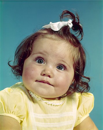 simsearch:846-02793958,k - 1960s BRUNETTE BABY GIRL ROUND CHUBBY FACE YELLOW DRESS RIBBON TOPKNOT INTERESTED SINCERE FACIAL EXPRESSION Stock Photo - Rights-Managed, Code: 846-03163969