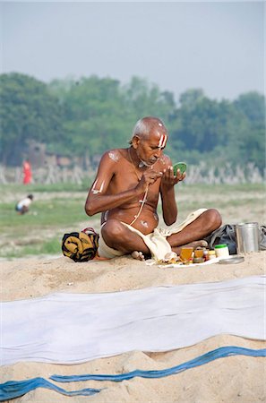 Vishnaivite holy man sitting cross legged, preparing for morning puja, applying sandalwood tilaks on forehead and arms, wearing simple white dhoti and sacred Hindu string, Patna, Bihar, India, Asia Stock Photo - Rights-Managed, Code: 841-05785477