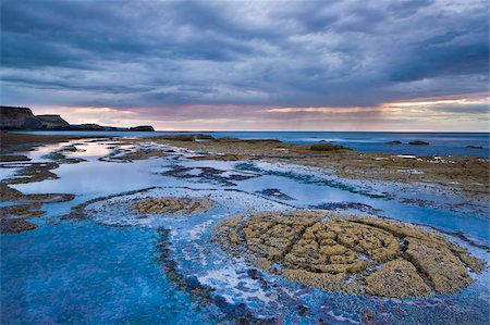 Rock formations on the shale shelf at Saltwick Bay, with stormy clouds and rain showers in the distance, North Yorkshire, Yorkshire, England, United Kingdom, Europe Stock Photo - Rights-Managed, Code: 841-05848832