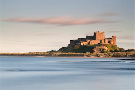 Bamburgh Castle bathed in golden evening light overlooking Bamburgh Bay with the sea filling the foreground, Northumberland, England, United Kingdom, Europe Foto de stock - Con derechos protegidos, Código: 841-05959819