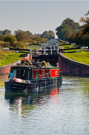 A canal boat leaving the famous series of locks at Caen Hill on the Kennet and Avon Canal, Wiltshire, England, United Kingdom, Europe Fotografie stock - Rights-Managed, Codice: 841-06034296