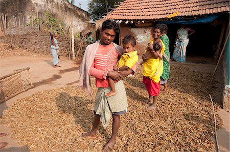 Young father of Desia Kondh tribe holding his son outside his house, standing on crop of drying millet, Bissam Cuttack, Orissa, India, Asia Stock Photo - Rights-Managed, Code: 841-06343896