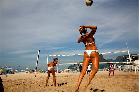 Two young women wearing bikinis sitting back to back on Ipanema beach, Rio  De Janeiro, Brazil stock photo