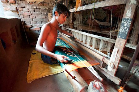 Young boy at domestic loom weaving patterned silk sari using several spools of silk, Vaidyanathpur weaving village, Orissa, India, Asia Foto de stock - Direito Controlado, Número: 841-06447676