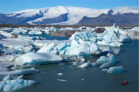 Canoeist paddles between icebergs on glacial lake at Jokulsarlon with snow on the massive icecap of Vatnajokull behind, Iceland, Polar Regions Fotografie stock - Rights-Managed, Codice: 841-06502805