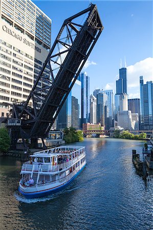 Tour boat passing under a raised disused railway bridge on the Chicago River, Downtown towers in the background, Chicago, Illinois, United States of America, North America Photographie de stock - Rights-Managed, Code: 841-06616670