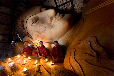 Three novice Buddhist monks sitting by a large reclining Buddha in the light of candles, near Shwesandaw Paya, Bagan, Myanmar (Burma), Asia Foto de stock - Con derechos protegidos, Código: 841-06805730