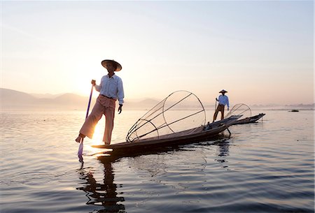 simsearch:841-07206250,k - Intha leg rowing fishermen at dawn on Inle Lake who row traditional wooden boats using their leg and fish using nets stretched over conical bamboo frames, Inle Lake, Shan State, Myanmar (Burma), Asia Stock Photo - Rights-Managed, Code: 841-06805749