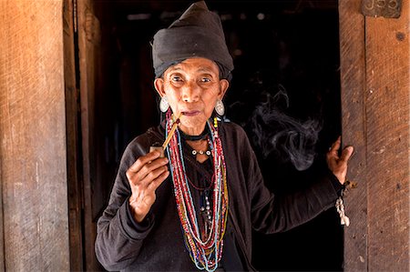 Woman of the Ann tribe in traditional black dress and colourful beads smoking a pipe in the doorway of her home in a hill village near Kengtung (Kyaingtong), Shan State, Myanmar (Burma), Asia Foto de stock - Con derechos protegidos, Código: 841-06805764