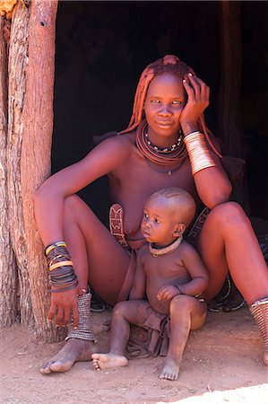 Young Himba woman, with baby, wearing traditional dress and jewellery and with her skin covered in Otjize, a mixture of butterfat and ochre, Kunene Region, formerly Kaokoland, Namibia, Africa Stockbilder - Lizenzpflichtiges, Bildnummer: 841-06805776