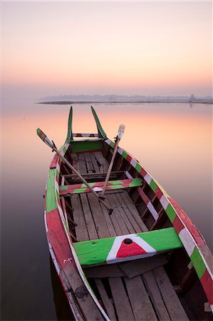 Traditional rowing boat moored on the edge of flat calm Taungthaman Lake at dawn with the colours of the sky reflecting in the calm water, close to the famous U Bein teak bridge, near Mandalay, Myanmar (Burma), Asia Photographie de stock - Rights-Managed, Code: 841-07081635