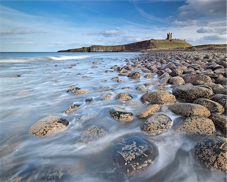 The ruins of Dunstanburgh Castle overlooking the boulder strewn shores of Embleton Bay, Northumberland, England, United Kingdom, Europe Photographie de stock - Rights-Managed, Code: 841-07355156