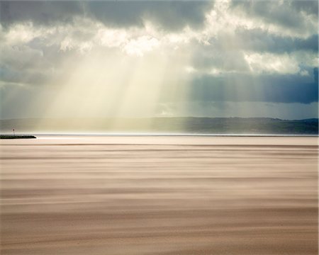 Crepuscular rays through a stormy sky while shifting sands create a cloud underfoot as wind whistles across the beach, West Kirkby, Wirral, England, United Kingdom, Europe Stockbilder - Lizenzpflichtiges, Bildnummer: 841-08527758