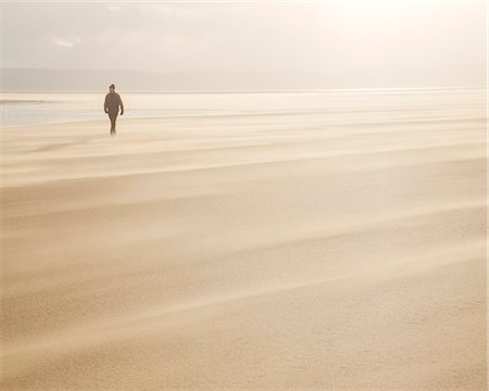 simsearch:841-07355214,k - Man walking across a windy beach with dry shifting sands creating a cloud underfoot, West Kirkby, Wirral, England, United Kingdom, Europe Stock Photo - Rights-Managed, Code: 841-08527759