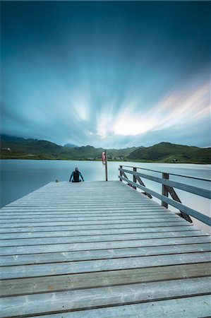 Hiker on wooden deck admires the sea illuminated by blue lights at night, Holdalsvatnet, Vestvagoy, Lofoten Islands, Norway, Scandinavia, Europe Foto de stock - Con derechos protegidos, Código: 841-08887159