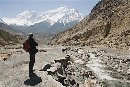 simsearch:6119-08740458,k - Trekker enjoys the view on the Annapurna circuit trek, Jomsom, Himalayas, Nepal. The high peak in the distance is 7021m Nilgiri, forming part of a wall known as The Grand Barrier. Foto de stock - Con derechos protegidos, Código: 841-02718731