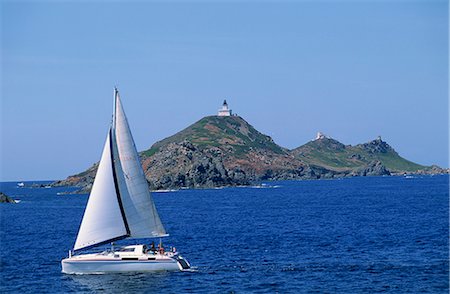 sailing ocean islands - Sailing boat with the Semaphore Lighthouse behind, Iles Sanguinaires, island of Corsica, France, Mediterranean, Europe Stock Photo - Rights-Managed, Code: 841-02713119