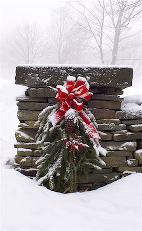 A snow covered Christmas wreath of pine branches, red berries and ribbon hanging on a stone wall, Rensselaervile, New York, United States of America, North America Stock Photo - Rights-Managed, Code: 841-02899922